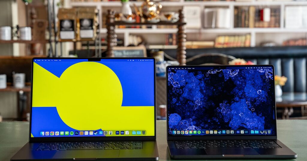 The 16-inch MacBook Pro with M4 Max (left) next to a 14-inch MacBook Pro with M4 (right) on a green tabletop in a cafe.