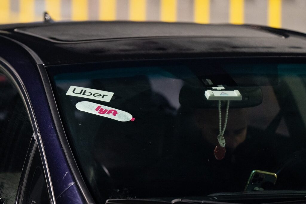 Uber and Lyft logos displayed in a car's windshield.