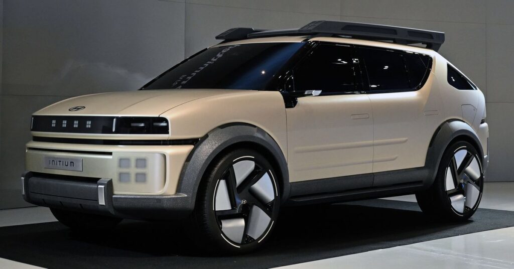 tan colored SUV on a show floor with black backdrop, four pixel lights on the grille.