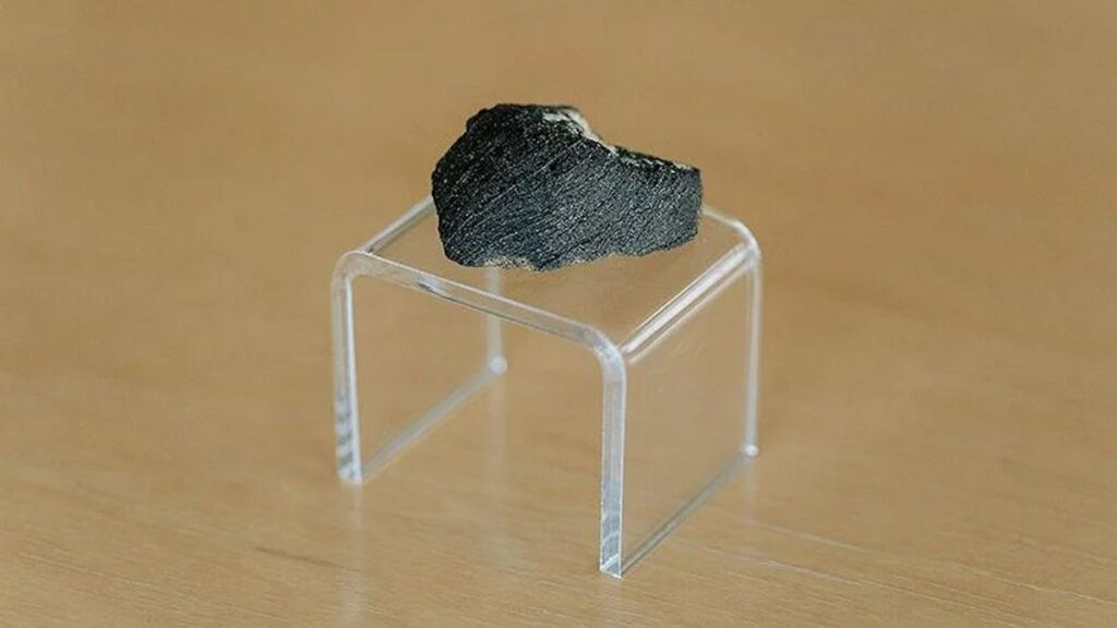 A small black meteorite on an acrylic stand