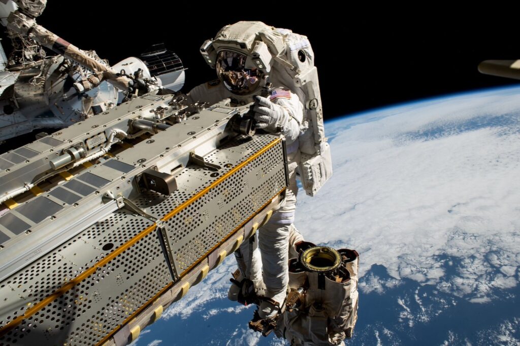 NASA astronaut Woody Hoburg rides the Canadarm2 robotic arm while maneuvering a roll-out solar array during a spacewalk in November 2023.