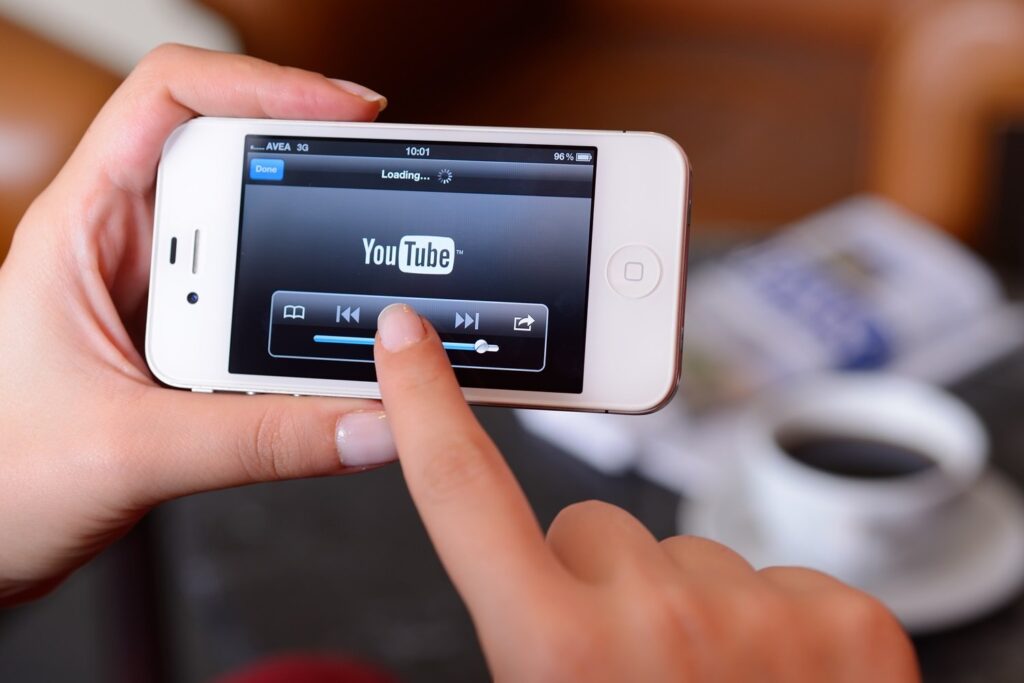 September 19, 2012: Woman hands holding an Apple iPhone 4. iPhone 4 displaying loading video screen of Youtube application.