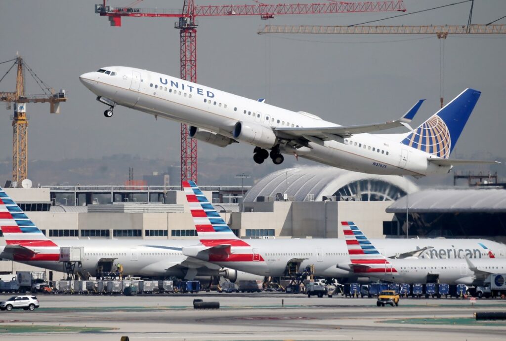 A United Airlines plane takes off above American Airlines planes on the tarmac at Los Angeles International Airport (LAX) on October 1, 2020