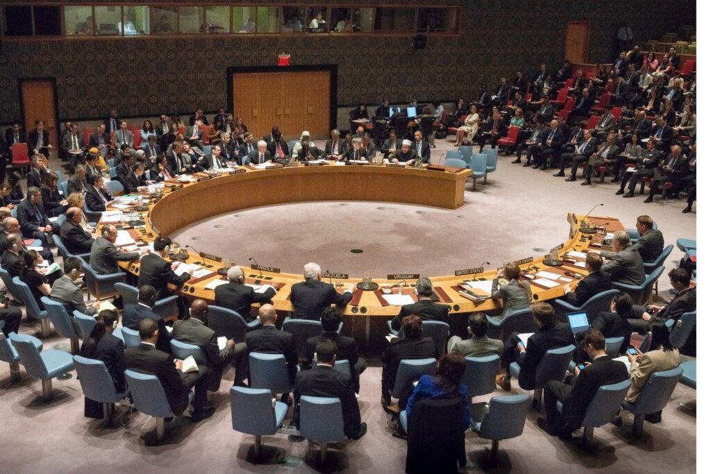 An overhead shot of delegates to the UN Security Council sitting around a circular conference area.