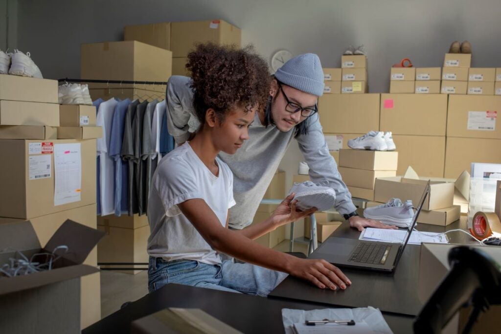 Mixed race couple of Asian man and African-American woman online seller confirming orders from customer on laptop.