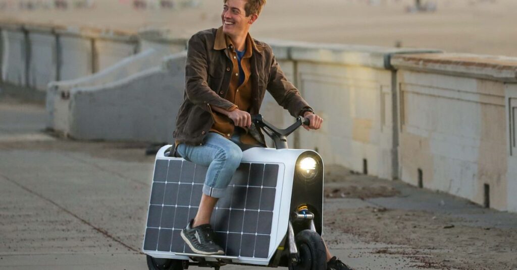 A rider sitting on the Lightfoot scooter propped up with one foot.