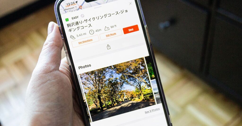 Person holding iPhone showing the new Strava Recommended Routes photo feature with a route in Tokyo.