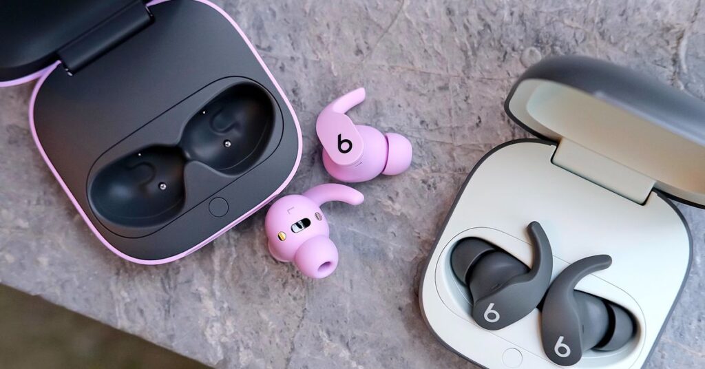 A photo of two pairs of Beats Fit Pro earbuds on a marble surface.