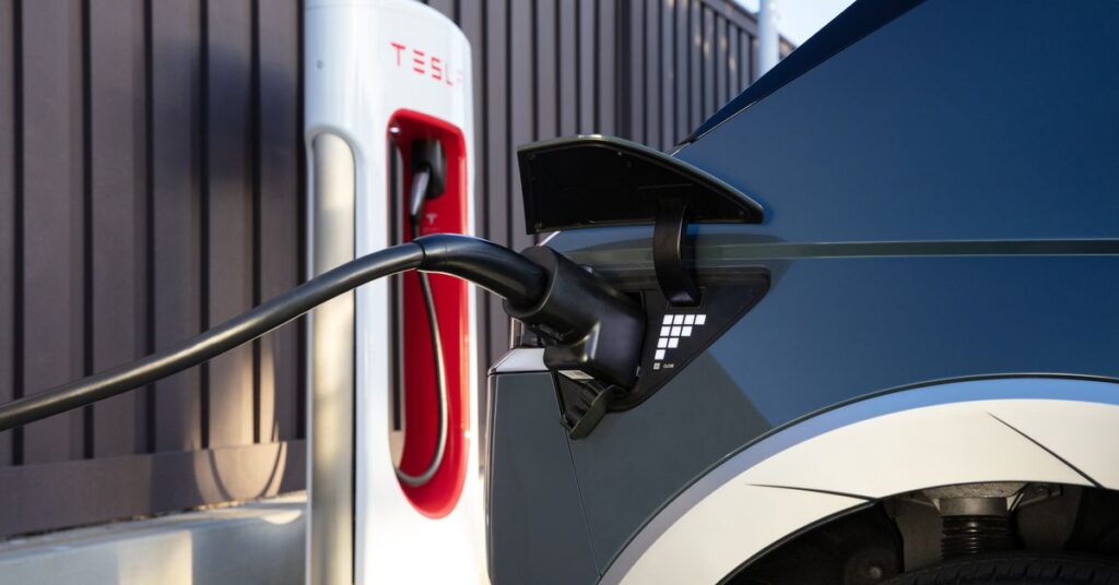 closeup of Ioniq 5 port on the rear right side of car with Tesla charging stall in background