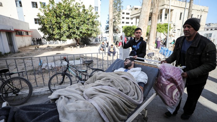 A man in a hospital bed is wheeled  outside the hospital