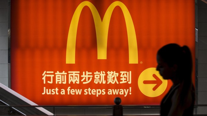 A woman walks past a brightly lit McDonald's sign in Hong Kong,