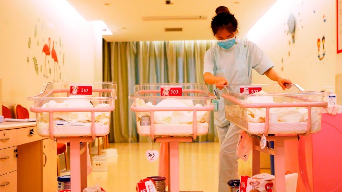 A woman wearing light blue scrubs looks after babies in a postpartum care centre in Shanghai